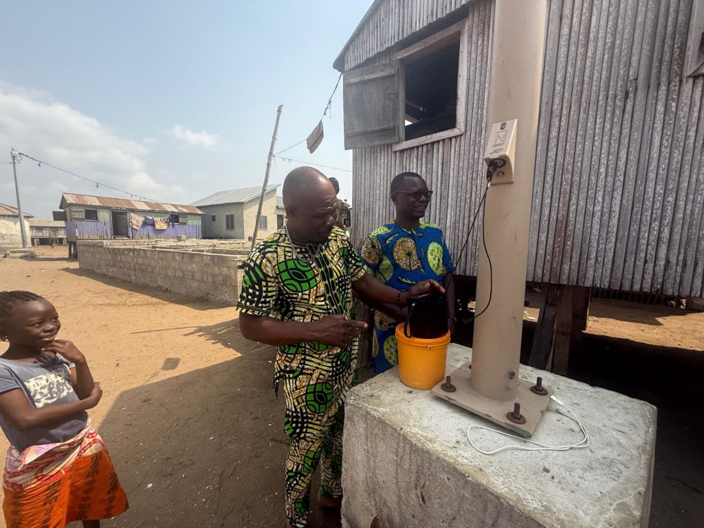 Homme rechargeant son enceinte portable grâce au module de charge USB Novload, installé sur tous les lampadaires solaires NOVEA ENERGIES